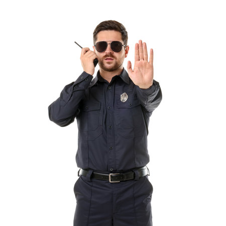 Policeman in uniform with walkie talkie showing stop gesture on white backgroundの写真素材