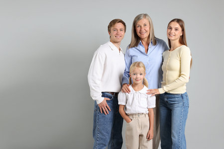 Portrait of senior woman with son and his family on light background. Space for text