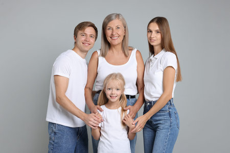 Portrait of senior woman with son and his family on light grey background
