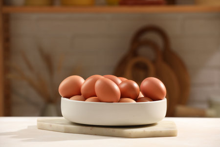 Raw chicken eggs in bowl on white table in kitchenの写真素材