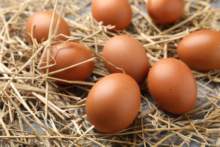 Raw chicken eggs and straw on table, closeup