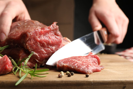 Woman cutting raw beef meat at table, closeupの写真素材