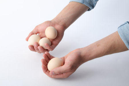 Man with raw chicken eggs on white background, closeupの写真素材