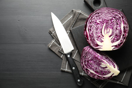 Cut fresh red cabbage and knife on black wooden table, flat lay. Space for textの写真素材