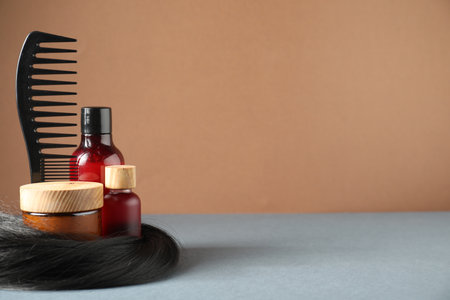 Hair lock, comb and cosmetic products on gray table. Space for textの写真素材