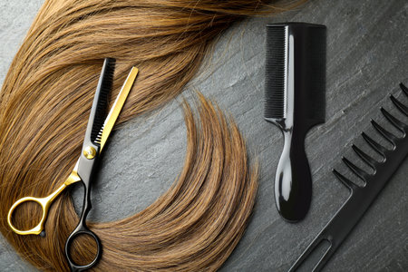 Beautiful hair strand and hairdresser's tools on gray background, flat layの写真素材