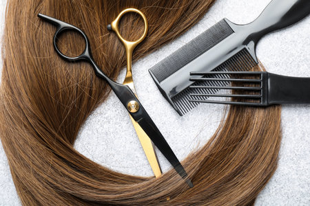 Beautiful hair strand and hairdresser's tools on light background, flat layの写真素材