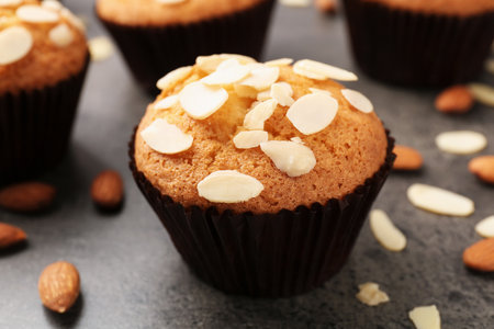 Tasty muffins with almond flakes and nuts on gray table, closeupの写真素材