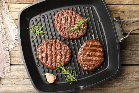 Pan with grilled patties and spices on wooden table, top viewの写真素材