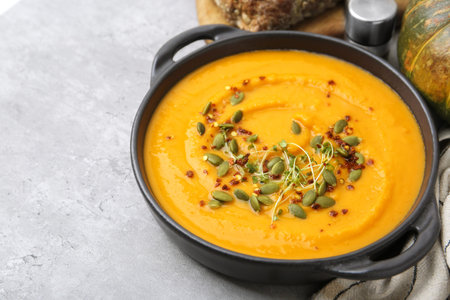 Delicious pumpkin soup served on gray table, closeup. Space for text