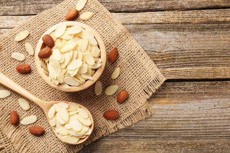 Fresh almond flakes and whole nuts on wooden table, flat lay. Space for textの写真素材