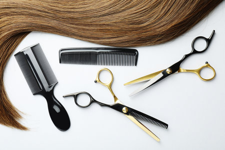 Beautiful hair strand and hairdresser's tools on white background, flat layの写真素材