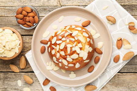 Tasty roll bun with almond flakes and nuts on wooden table, flat layの写真素材