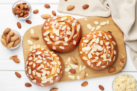 Tasty roll buns with almond flakes and nuts on white wooden table, flat layの写真素材
