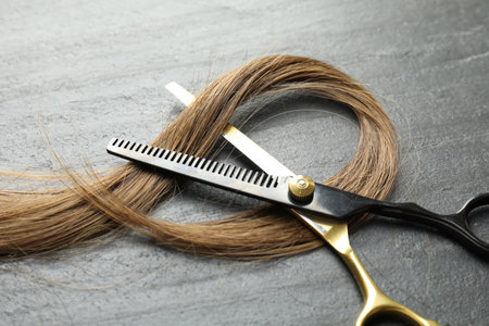 Beautiful hair strands and scissors on gray background, closeupの写真素材