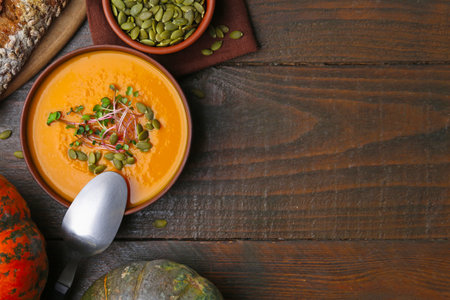 Delicious pumpkin soup served on wooden table, flat lay. Space for textの写真素材
