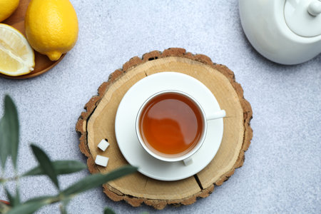 Aromatic black tea in cup, sugar, lemons and teapot on light gray table, flat layの写真素材