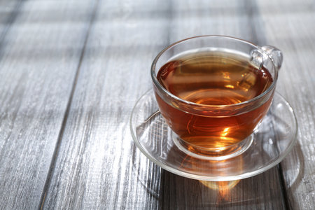 Aromatic black tea in glass cup on wooden table, closeup. Space for textの写真素材