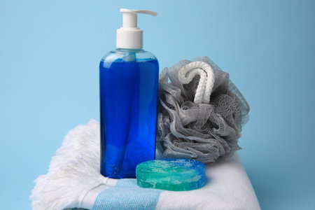 Gray shower puff, cosmetic products and towel on light blue backgroundの写真素材