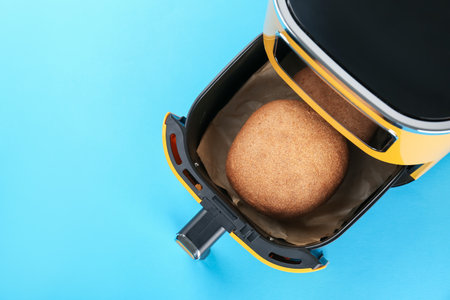 Air fryer with baked bread on light blue background, top view. Space for textの写真素材
