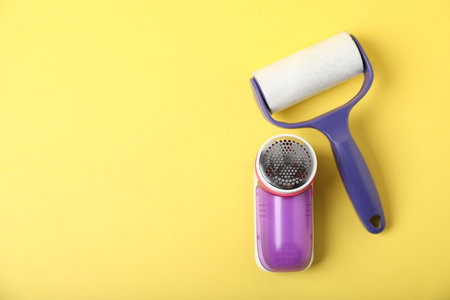 Lint roller and fabric shaver on yellow background, flat lay. Space for textの写真素材