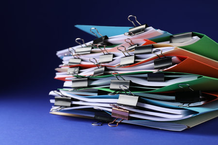 Many folders with documents and binder clips on blue background, closeupの写真素材