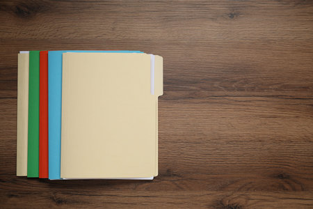 Many documents in folders on wooden table, top view. Space for text