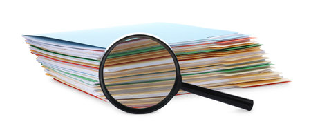 Stack of colorful folders with documents and magnifying glass isolated on whiteの写真素材
