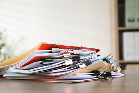 Many folders with documents and binder clips on wooden desk, closeup. Space for text