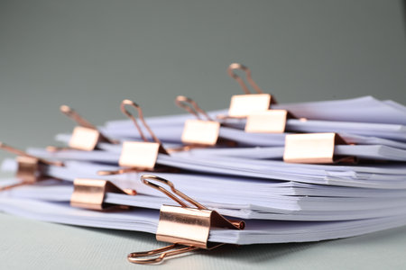Many documents with binder clips on light gray background, closeupの写真素材