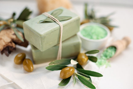 Natural soap bars and olives on white table, closeup