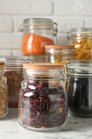 Glass jars with different products on white marble table, closeupの写真素材