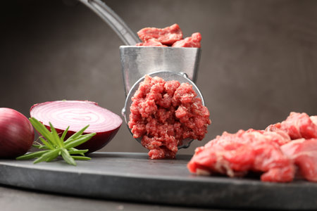 Making minced meat with grinder and spices on gray table, closeupの写真素材