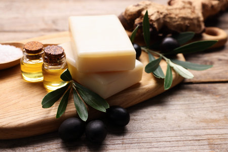 Handmade soap bars, olives, green leaves, sea salt, essential oils on wooden table, closeupの写真素材