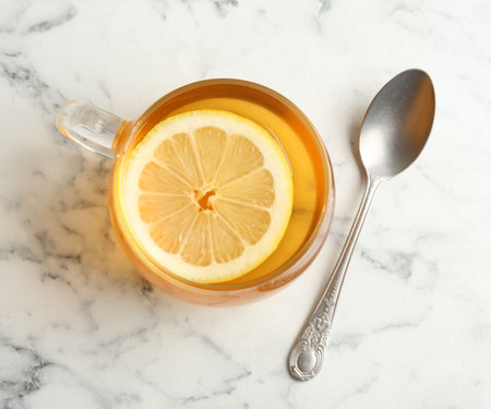 Aromatic tea with lemon in cup and spoon on white marble table, top viewの写真素材