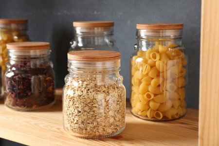 Glass jars with different products on wooden shelf, closeupの写真素材