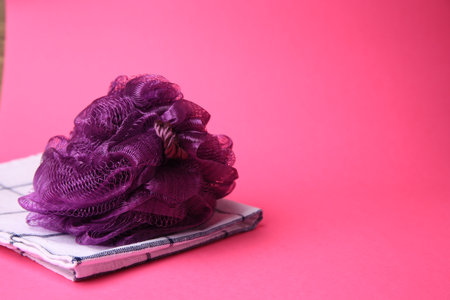 Purple shower puff and towel on pink background, space for textの写真素材