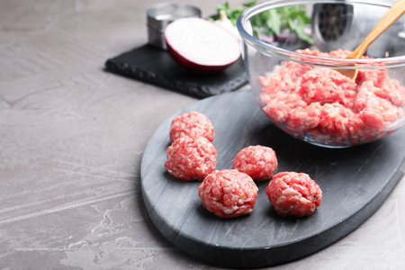 Raw meatballs and minced meat on gray table, closeup. Space for textの写真素材