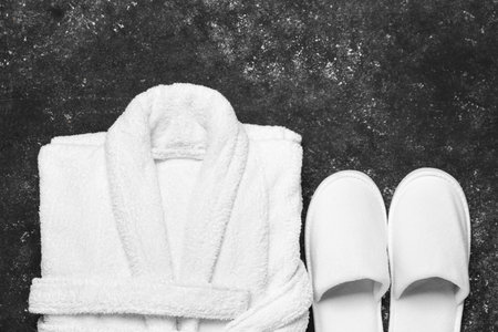Flat lay composition with bathrobe and slippers on black background, space for text. Spa and relaxの写真素材