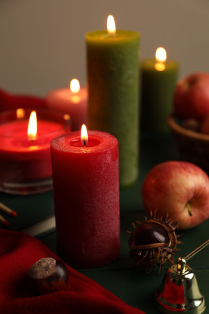 Composition with different burning candles on green table against gray background, closeup. Autumn atmosphereの写真素材