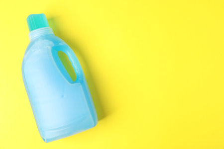 Bottle of laundry detergent on yellow background, top view. Space for textの写真素材