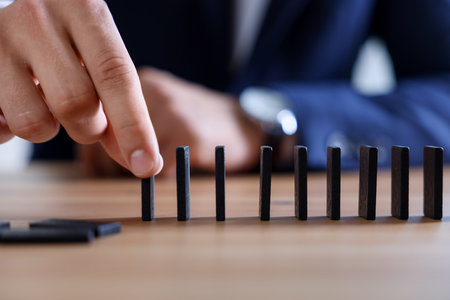 Risk. Man taking domino tale at wooden table, closeupの写真素材