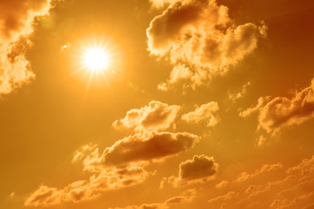 Bright sun and clouds in orange sky during hot summer weatherの写真素材