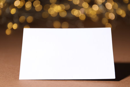 Blank card on brown background with blurred lights, closeup. Bokeh effectの写真素材