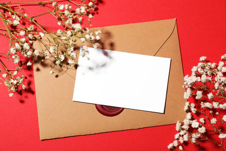 Blank card, envelope and beautiful flowers on red background, flat layの写真素材