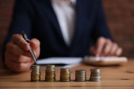 Man counting coins at wooden table indoors, selective focusの写真素材