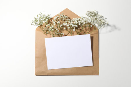 Blank card, envelope and beautiful flowers on white background, flat layの写真素材