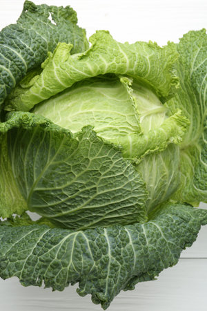 One fresh Savoy cabbage on white wooden table, top view