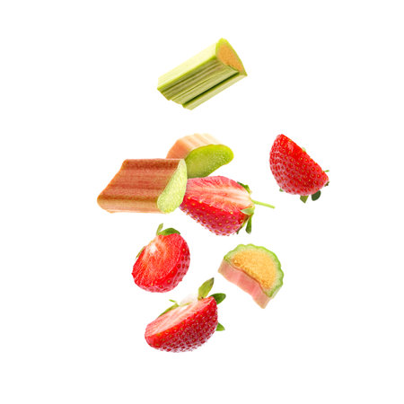 Fresh rhubarb pieces and strawberries flying in air against white backgroundの写真素材