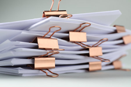 Many documents with binder clips on light gray background, closeupの写真素材
